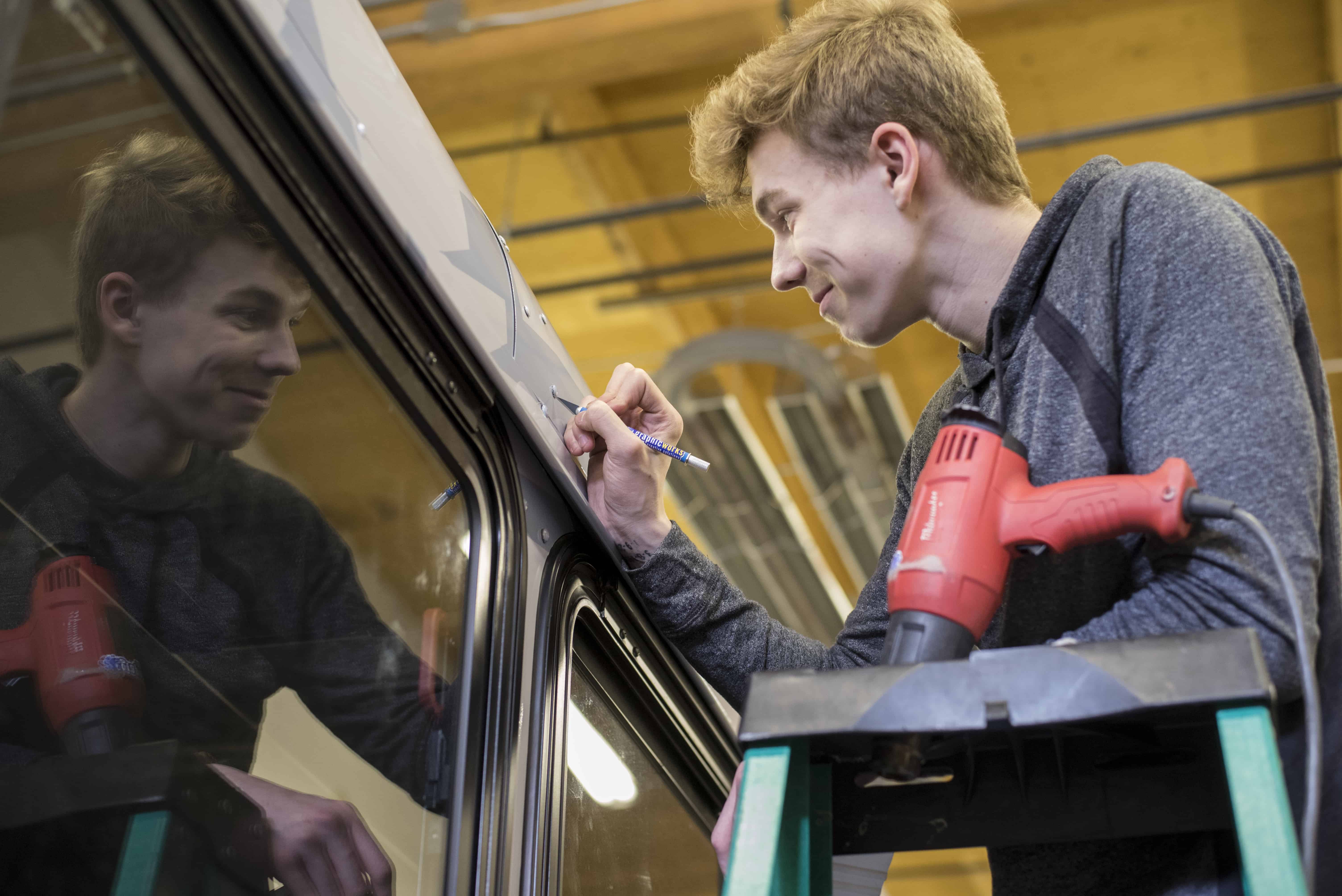 Donovan Conley-Smith smiles as he carefully cuts away excess material from a vehicle wrap – Photo Cred OHara Shipe