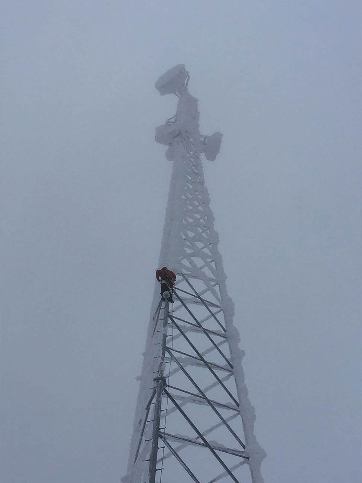 Leonardo DRS employee climbing an electrical tower during winter in Alaska