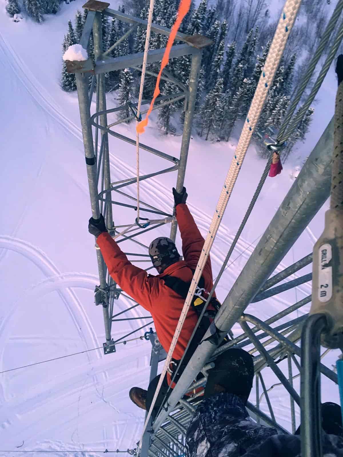 Leonardo DRS employee using a pulley system to move equipment at the top of an electrical tower