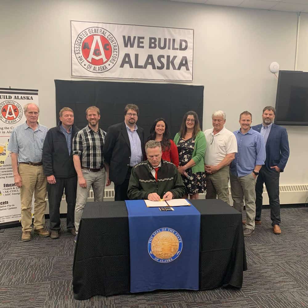 AGC members stand behind Governer Mike Dunleavy for a photo as during a signing event