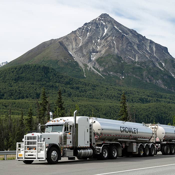 A Crowley truck transporting fuel with a mountain in the background