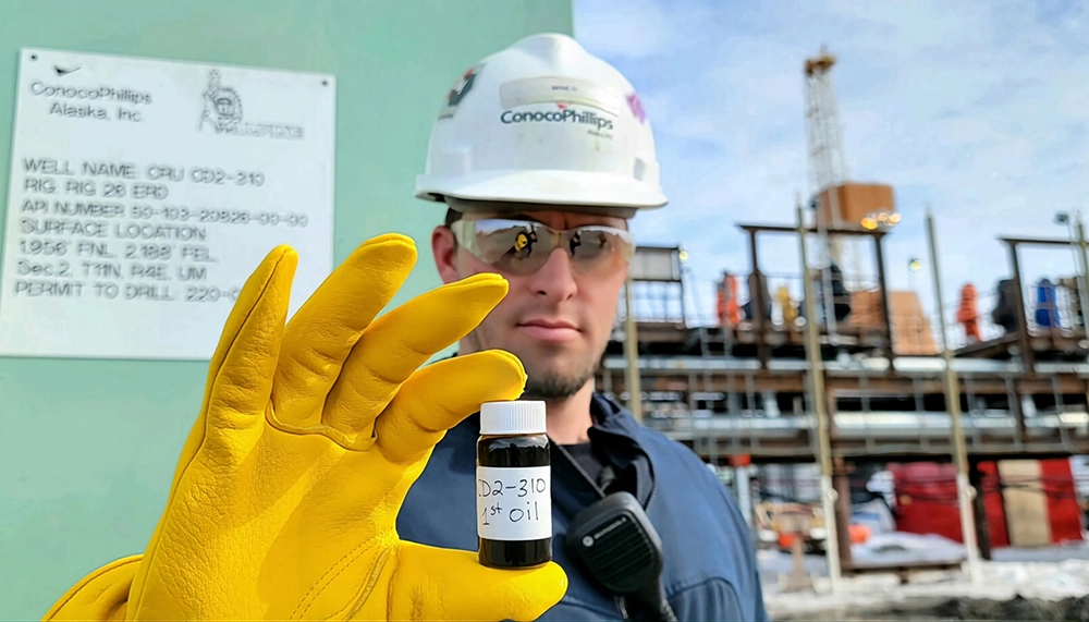 Man holding the first oil produced by the Fiord Kuparuk reservior