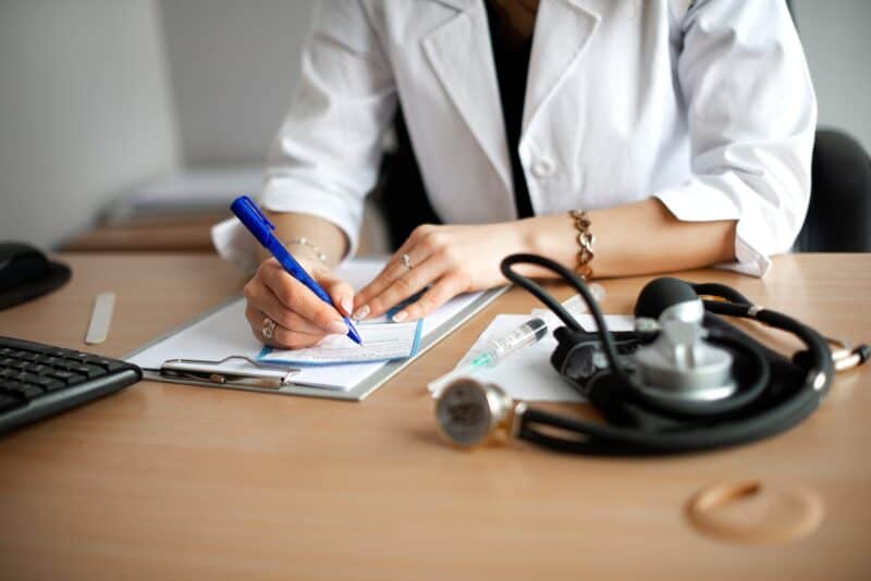 female-doctor-writes-a-prescription-at-his-desk-2022-11-09-08-15-46-utc